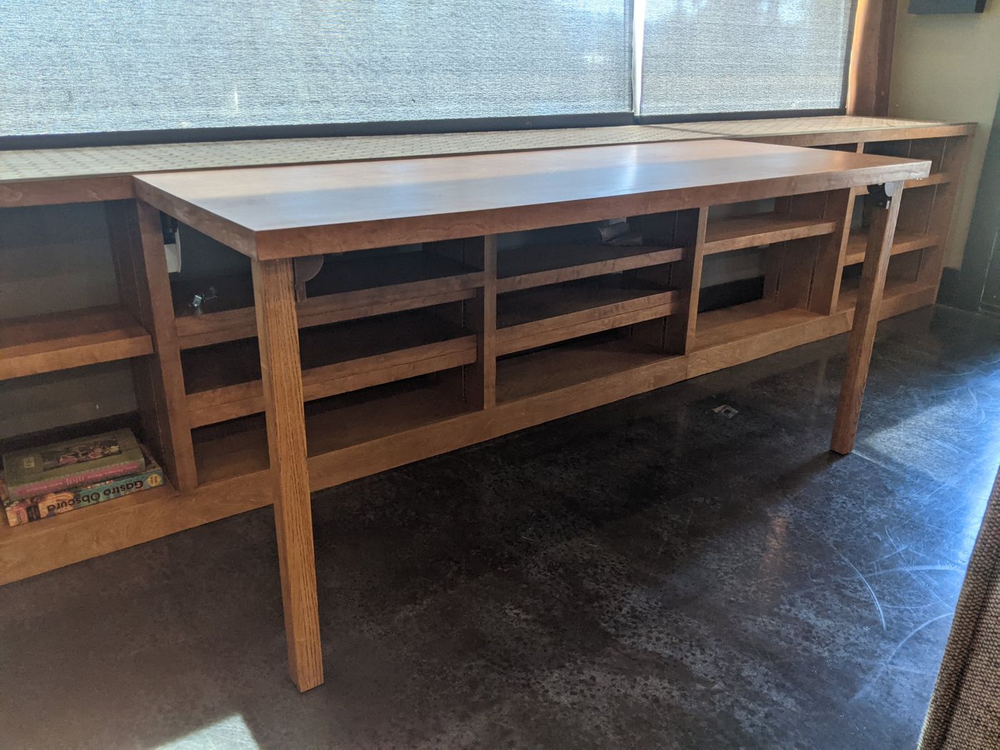 Built-in wood shelving under a window with a table top