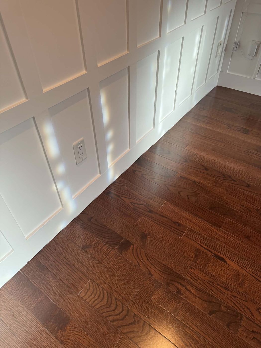 White panelled wall above dark hardwood floor
